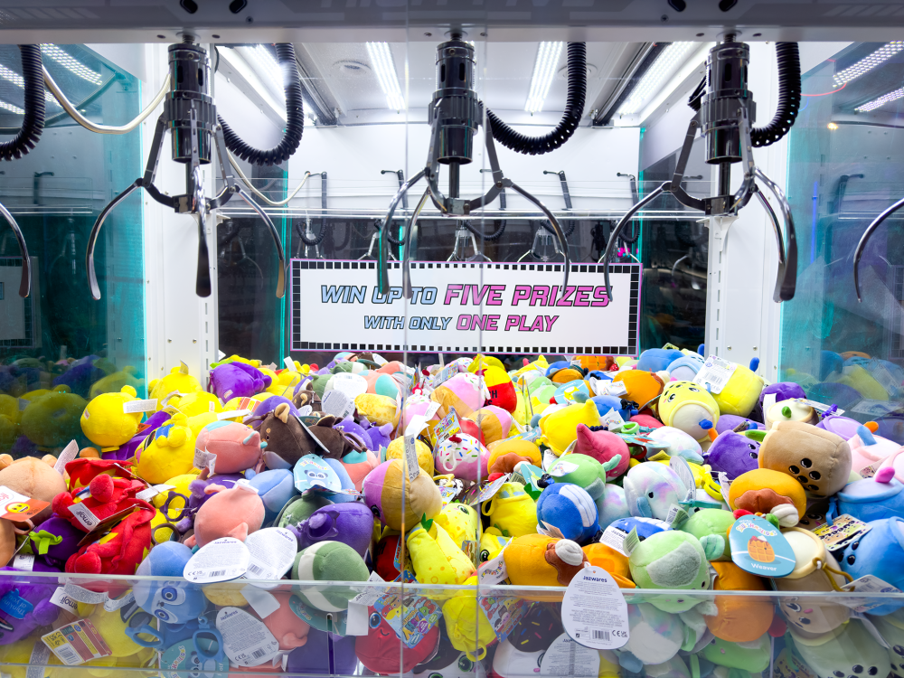 a photo showcasing vibrant colors of prizes to be collected by steel claws hanging on top. all plush stuff toys are colorful