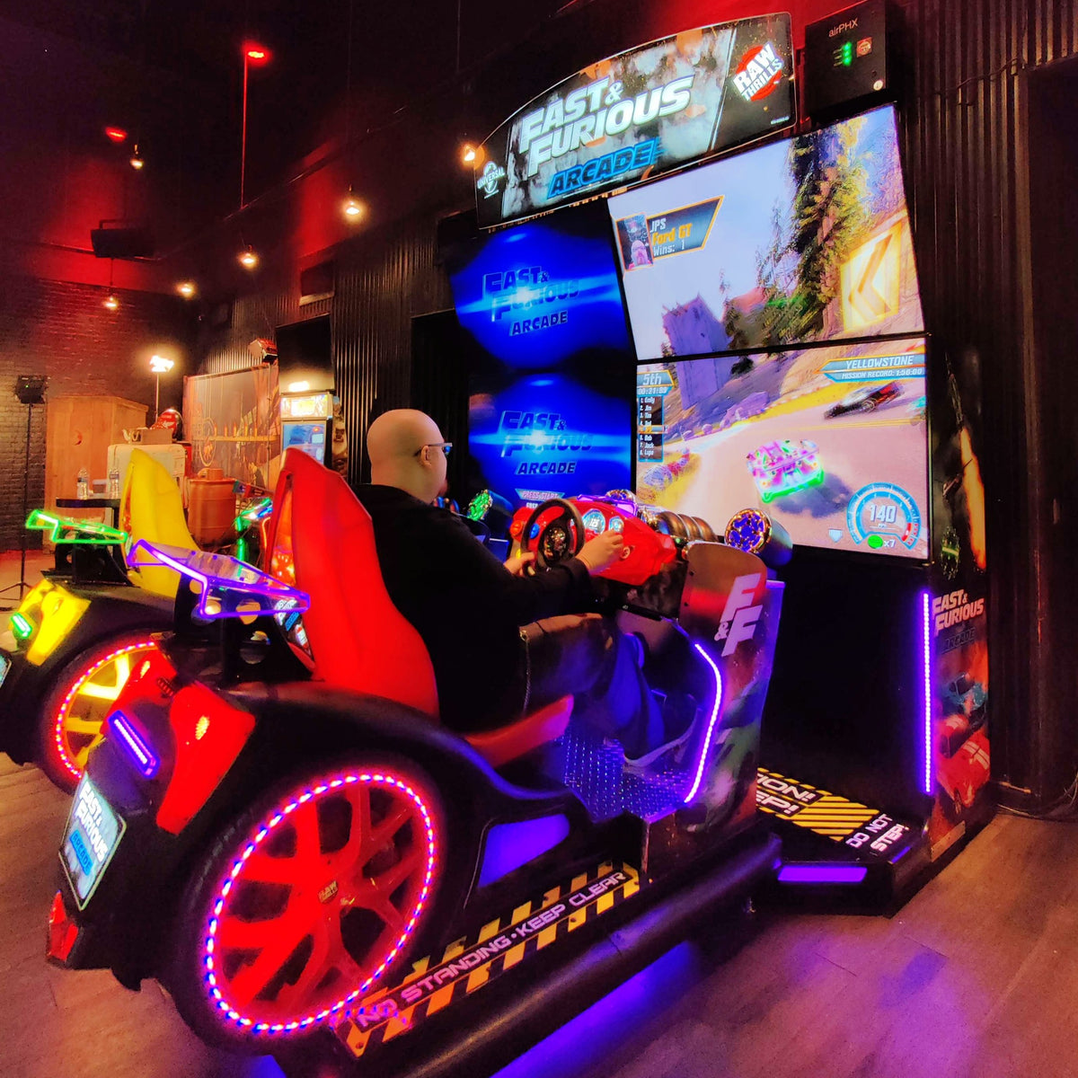 Fast & Furious Thrill-D motion racing arcade machine with dual 65-inch UHD screens, motion simulator, and 1–8 player linked cabinets