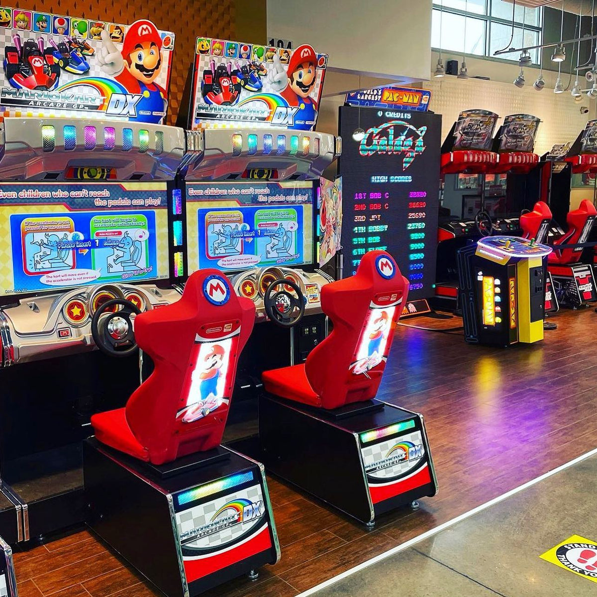 Mario Kart GP DX arcade driving game with 42-inch HD monitor, linkable 4-player racing, and rainbow LED cabinet.