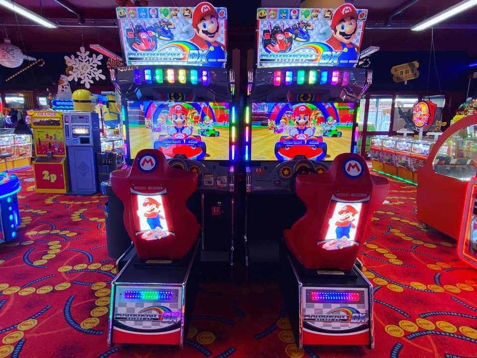 Mario Kart GP DX arcade driving game with 42-inch HD monitor, linkable 4-player racing, and rainbow LED cabinet.