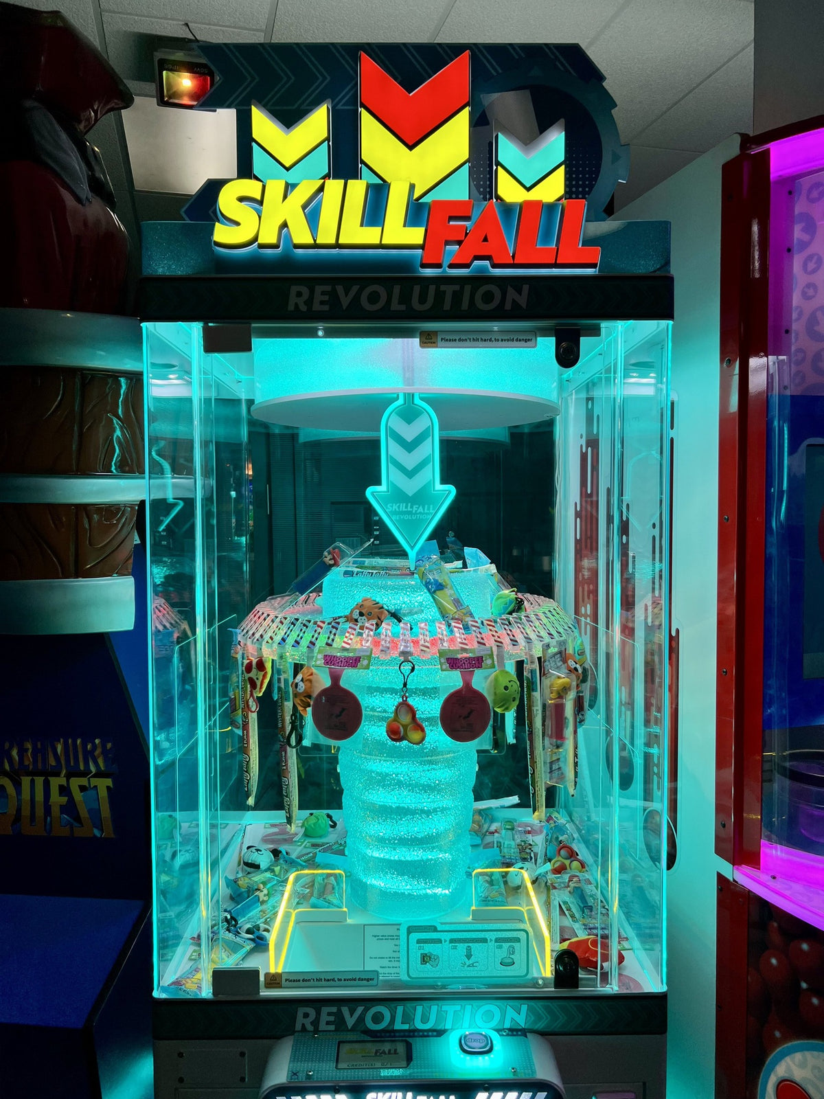Skill Fall Revolution blue cabinet prize redemption arcade machine with vertical drop gameplay and illuminated prize compartments