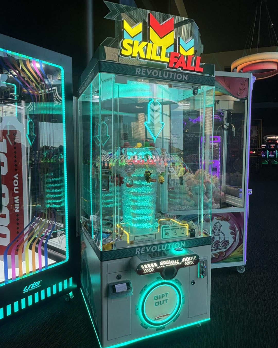 Skill Fall Revolution blue cabinet prize redemption arcade machine with vertical drop gameplay and illuminated prize compartments
